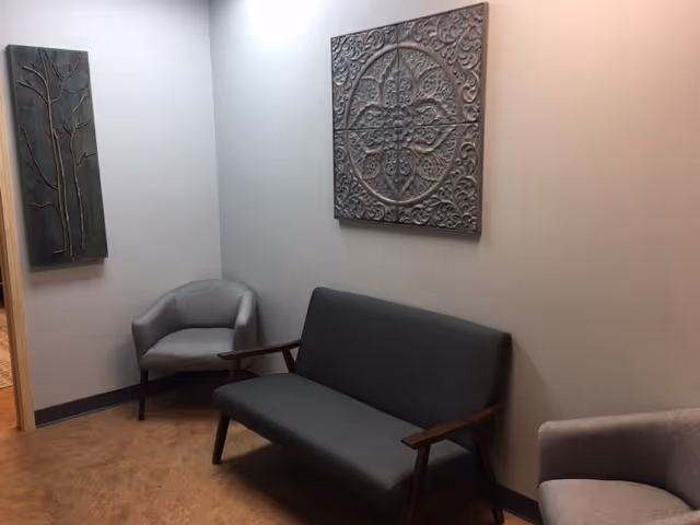 A small resident lounge with gray seating and decorative wall art.