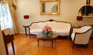Elegant living room with tufted white sofa, chairs, coffee table, and floral centerpiece.