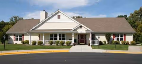 Single-story Brookdale Battle Creek building with white siding, red accents, and a curved driveway.