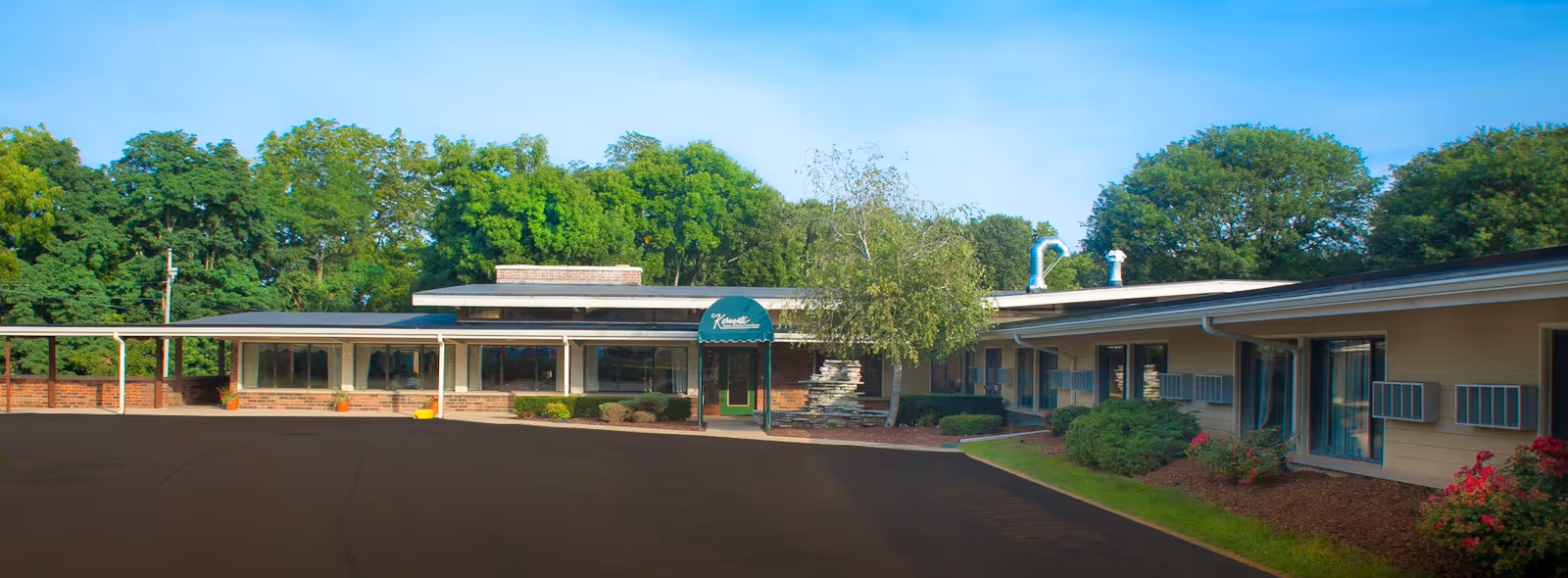 Exterior of Karmenta Center, a single-story senior living facility with a parking lot and trees.