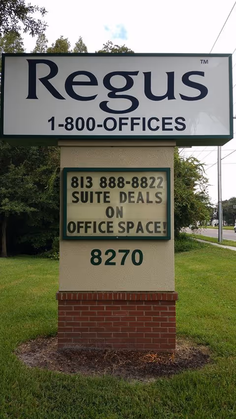 Large outdoor sign on a grassy area advertising Regus offices and suites.