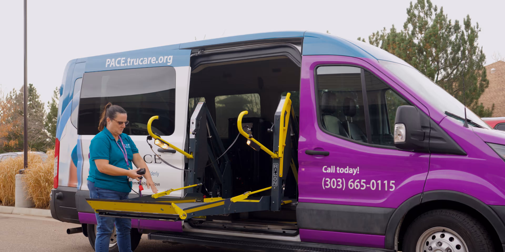 A staff member unloads a wheelchair lift from a TRU PACE service van outdoors.