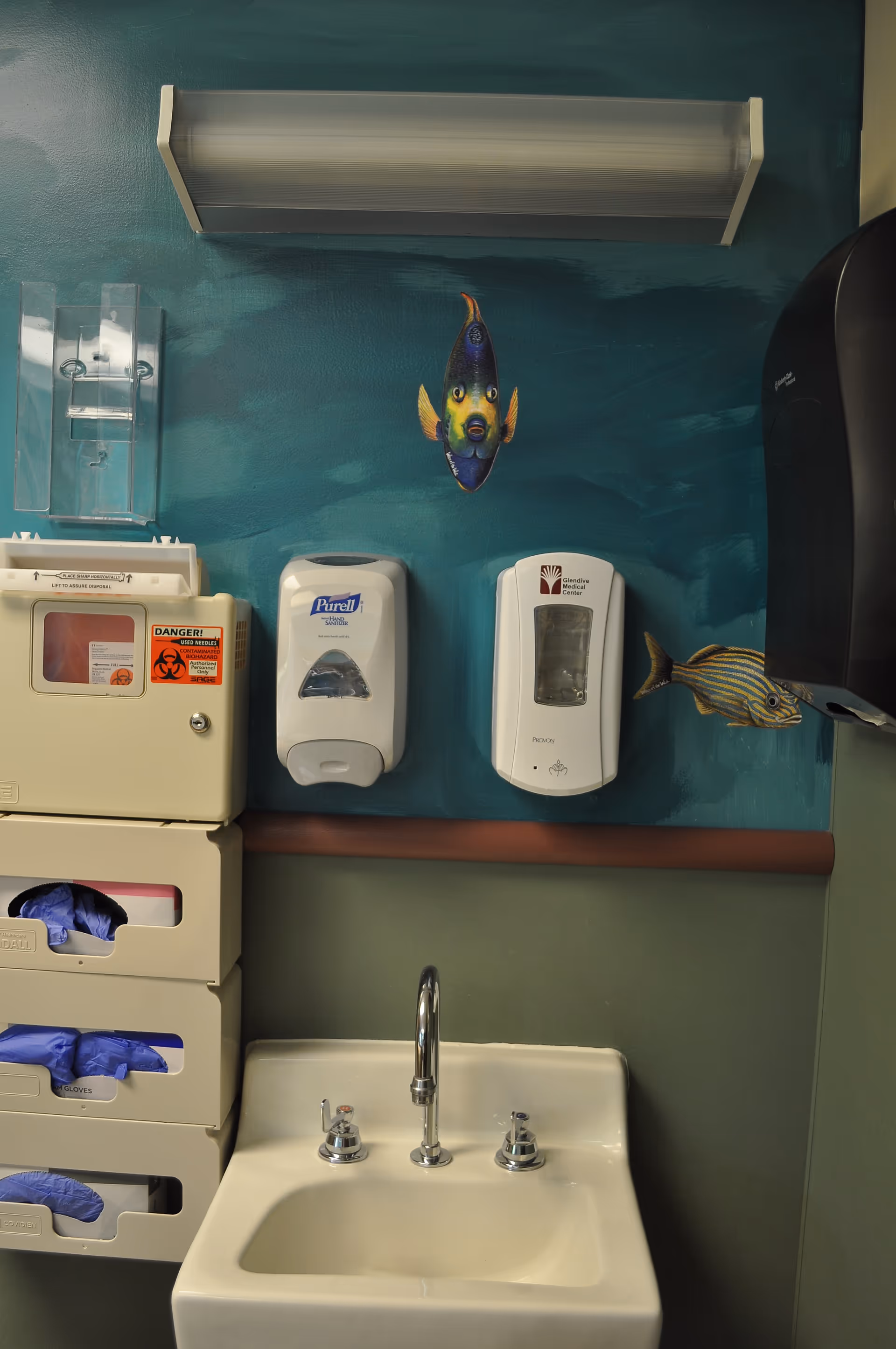 Interior medical room in Glendive Medical Center with wall-mounted dispensers, glove storage, and a sink.