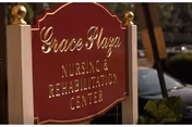 Red sign with gold lettering advertising a nursing and rehabilitation center.