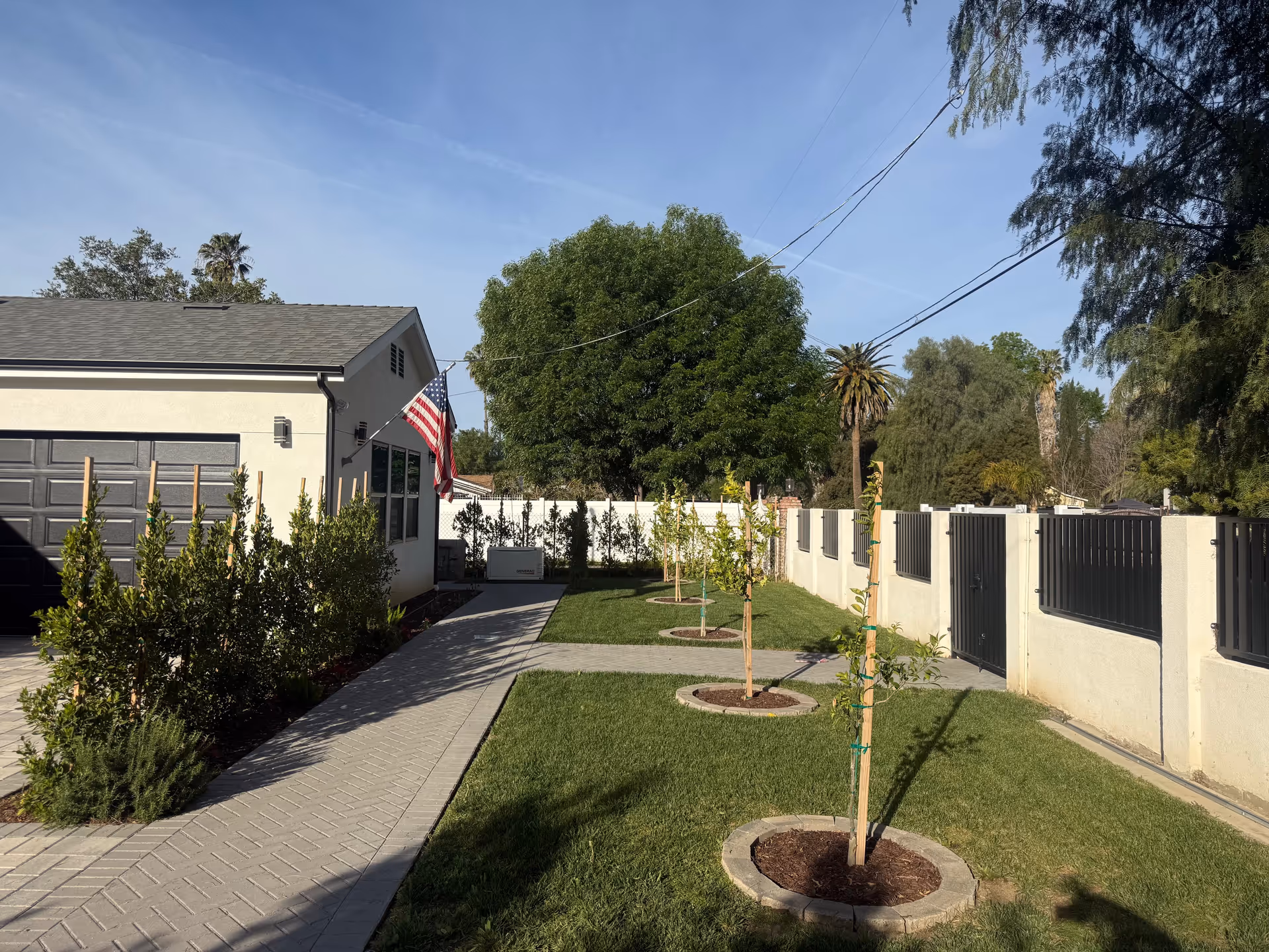 Exterior view of a single story assisted living facility with a manicured lawn, walkway, and fencing.