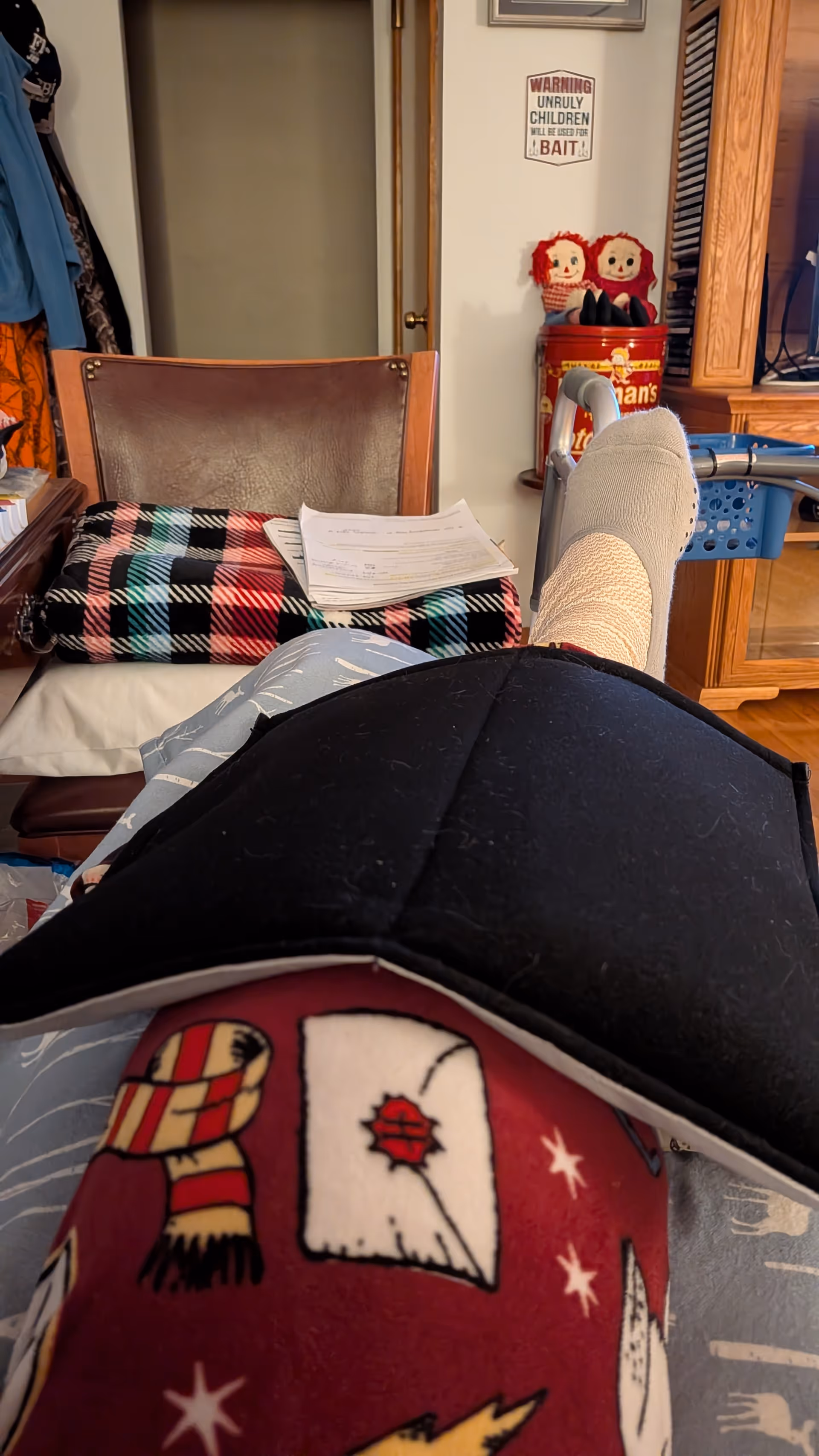 Resident's leg resting with a blanket and papers in a cluttered indoor living area.