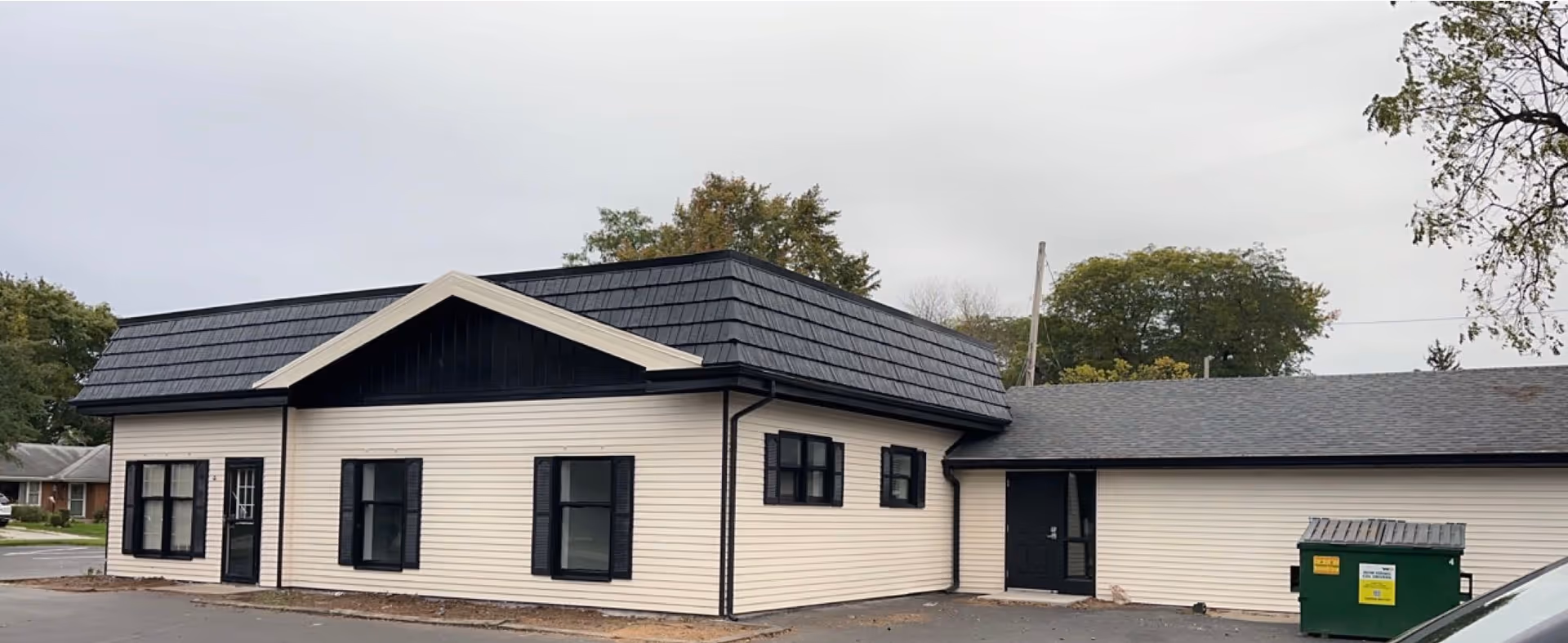 Single-story beige building with black trim and a dark sloped roof.