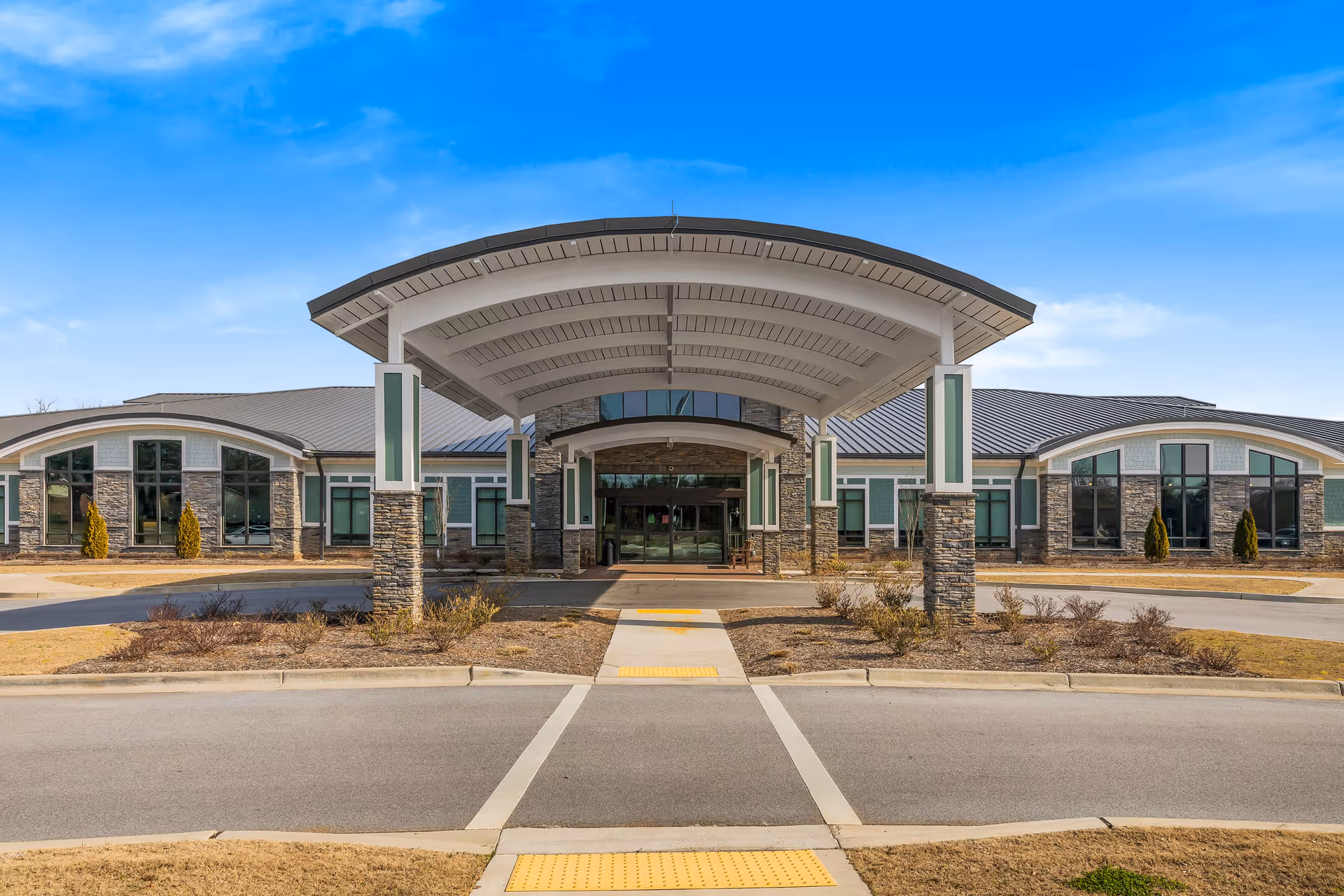 Exterior view of a modern senior living facility entrance with a large curved canopy.