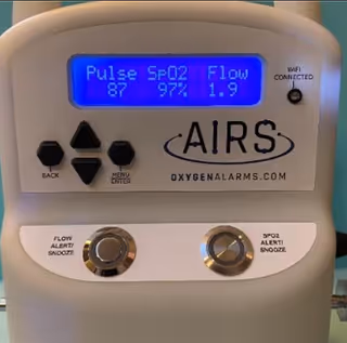 Close-up of AIRS oxygen alarm device mounted on a wall in a facility