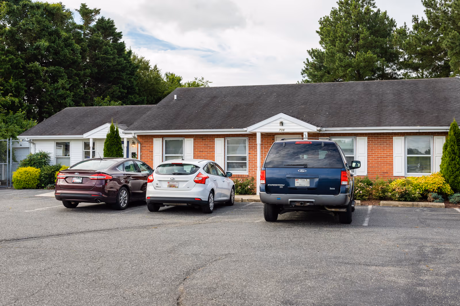 A single-story brick senior living facility with a parking lot and several cars.