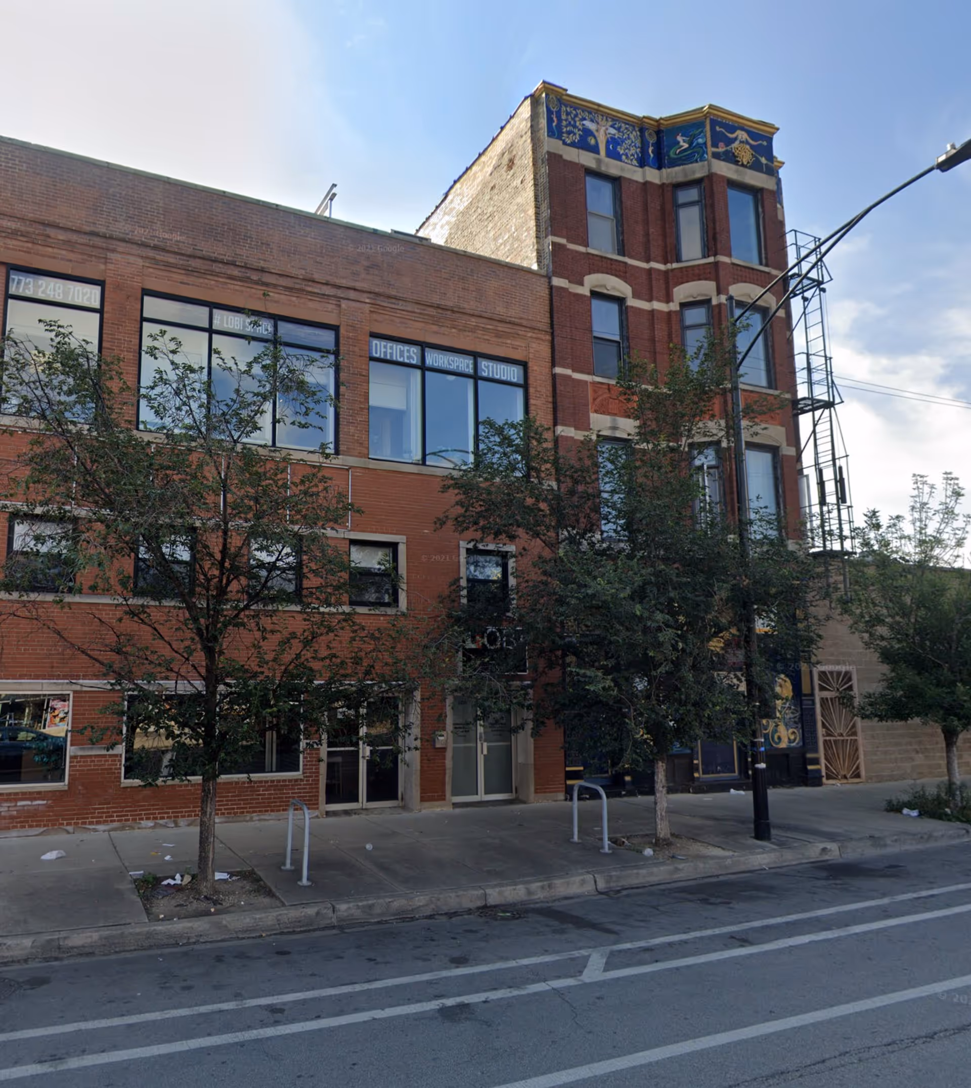 Brick, multi-story building along a street with trees and sidewalk.