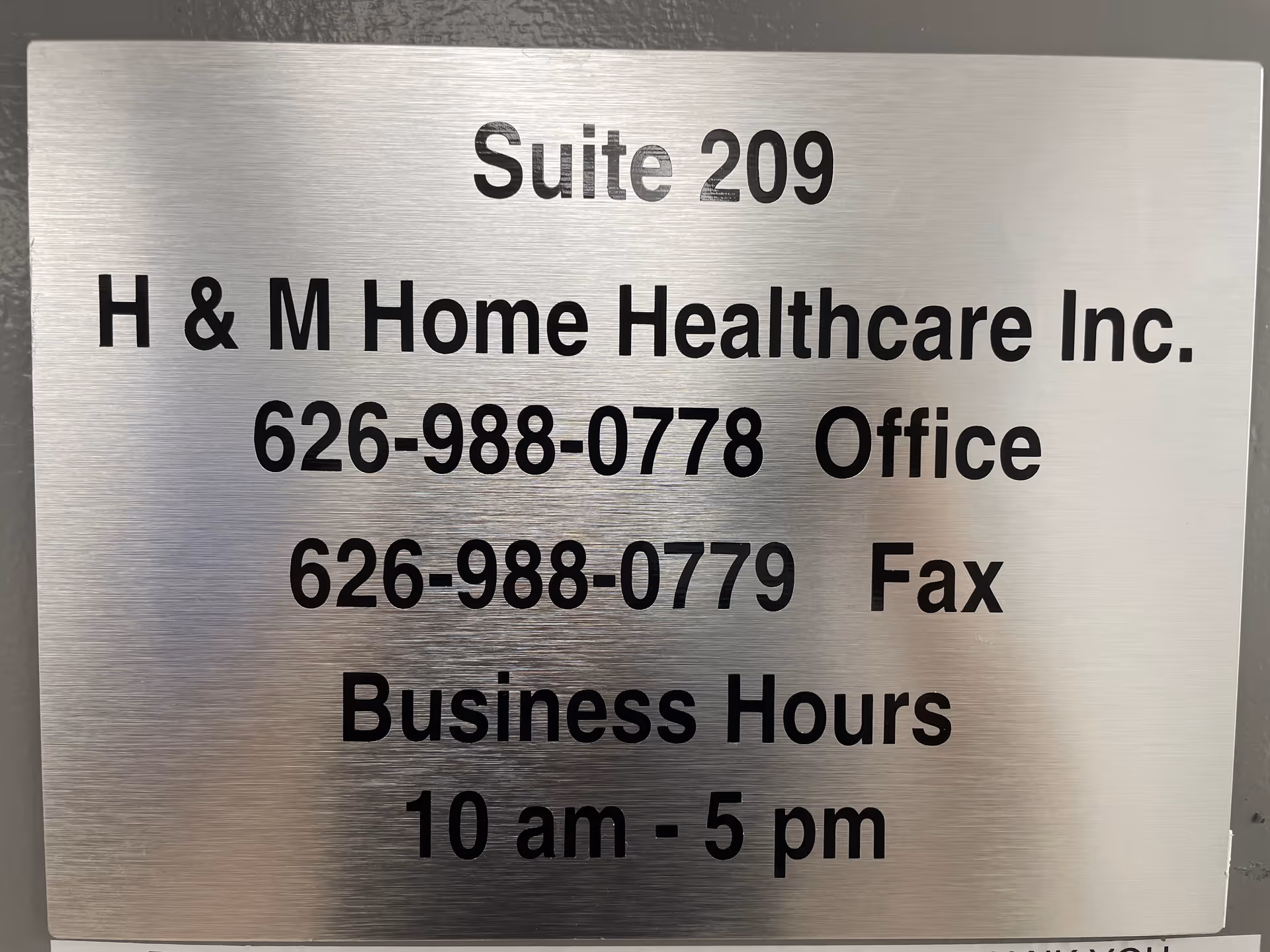 Brushed metal sign listing Suite 209 for H & M Home Healthcare Inc., with contact info.