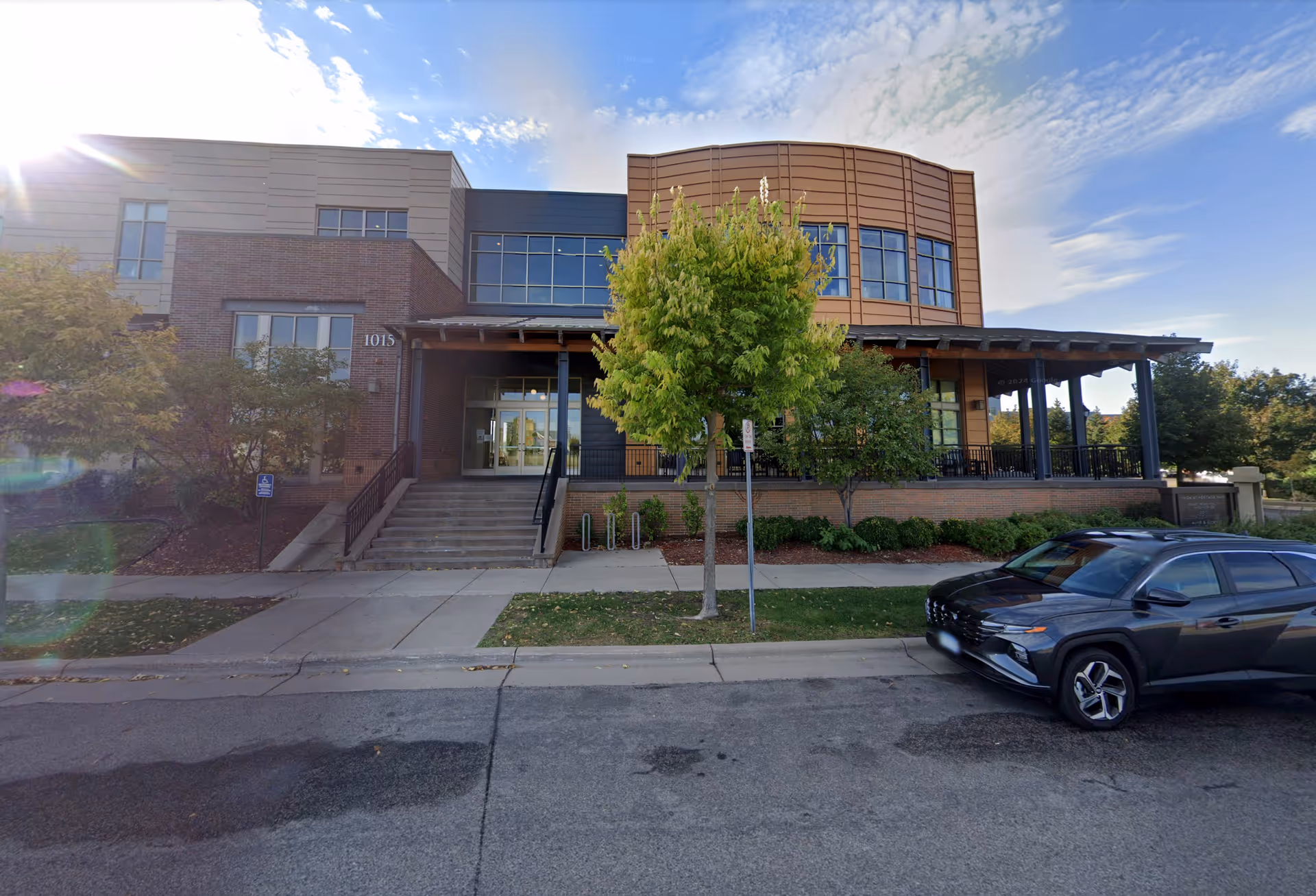 Grace Hospice exterior showing entrance, steps, trees, and a parked car.
