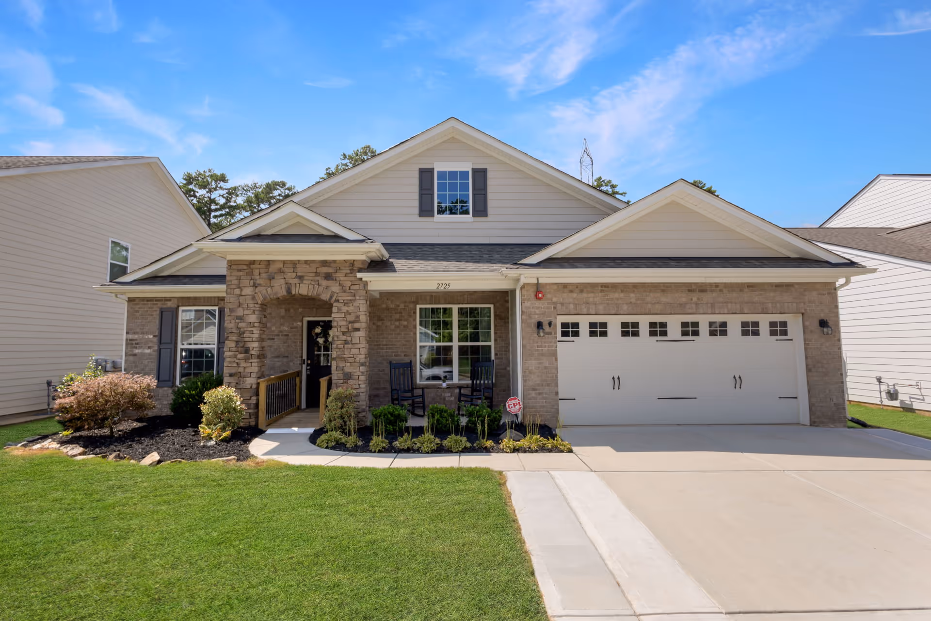 Exterior view of a brick/siding senior living building with a front porch and two-car garage.