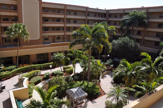Exterior courtyard of The Horizon Club with palm trees and a gazebo.