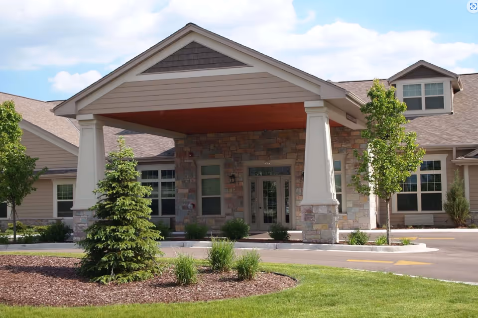 Exterior view of Sunrise Meadows Senior Living entrance with stone walls and a covered portico.