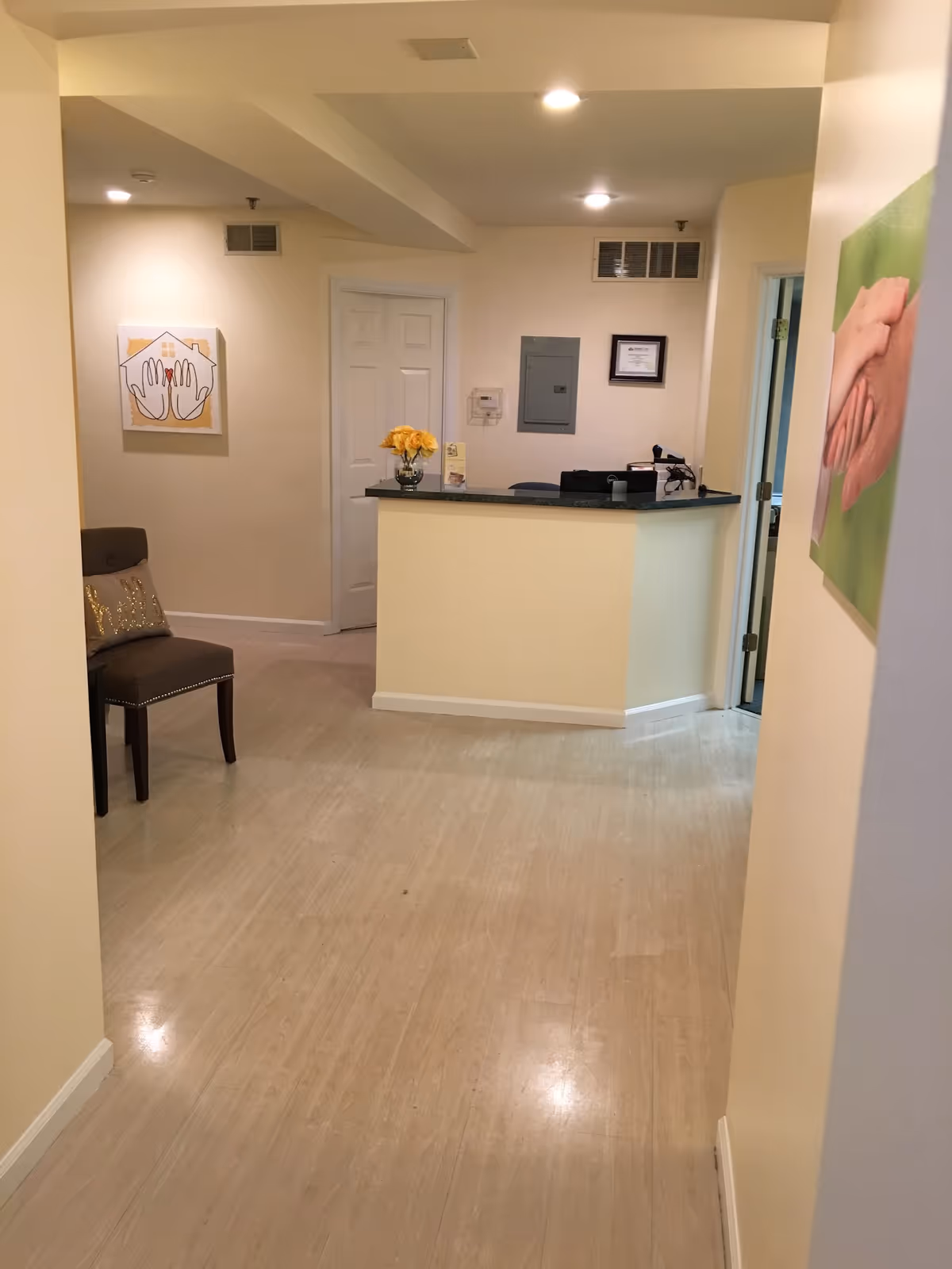Reception desk in a beige-walled senior living lobby with art and flowers.