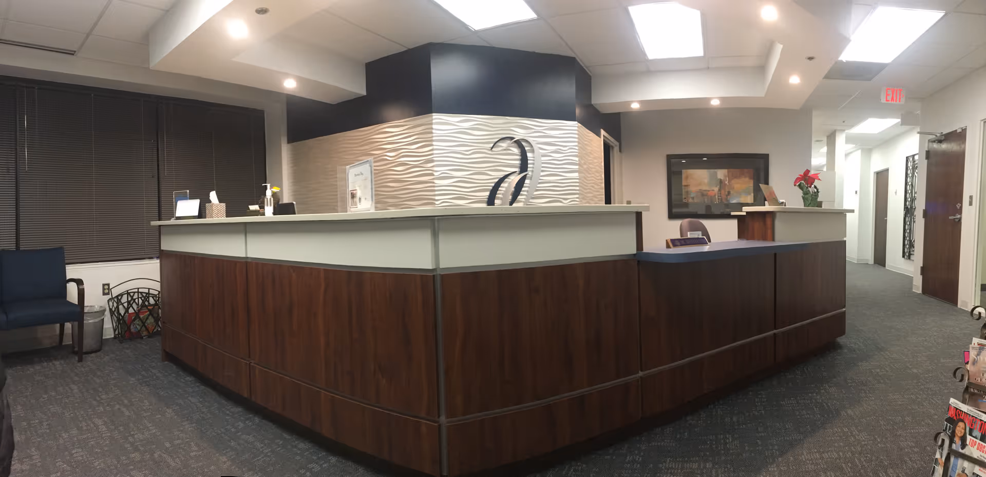 A curved wooden reception desk in a modern lobby with decorative wall behind.
