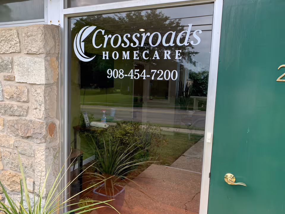 Glass door entrance reading Crossroads Homecare, with stone wall and green door on either side.