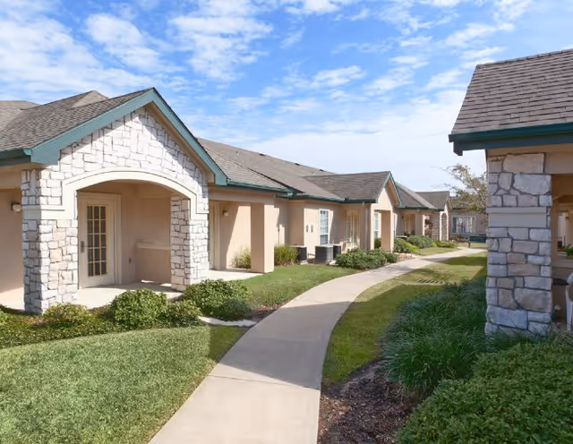 Row of single-story beige villas with stone accents along a curved walkway.