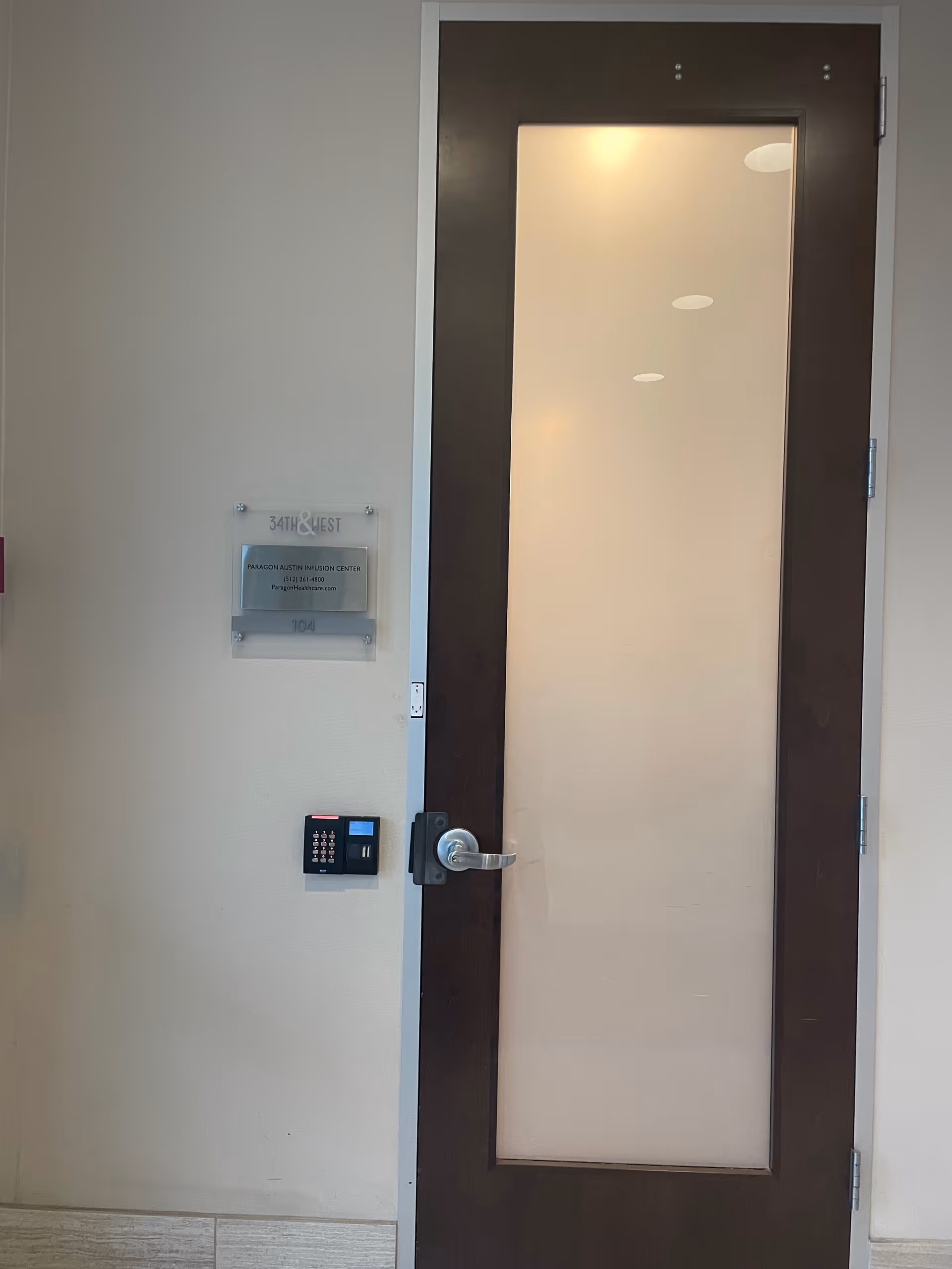 Interior doorway with dark-framed glass door, keypad lock, and wall plaque nearby.