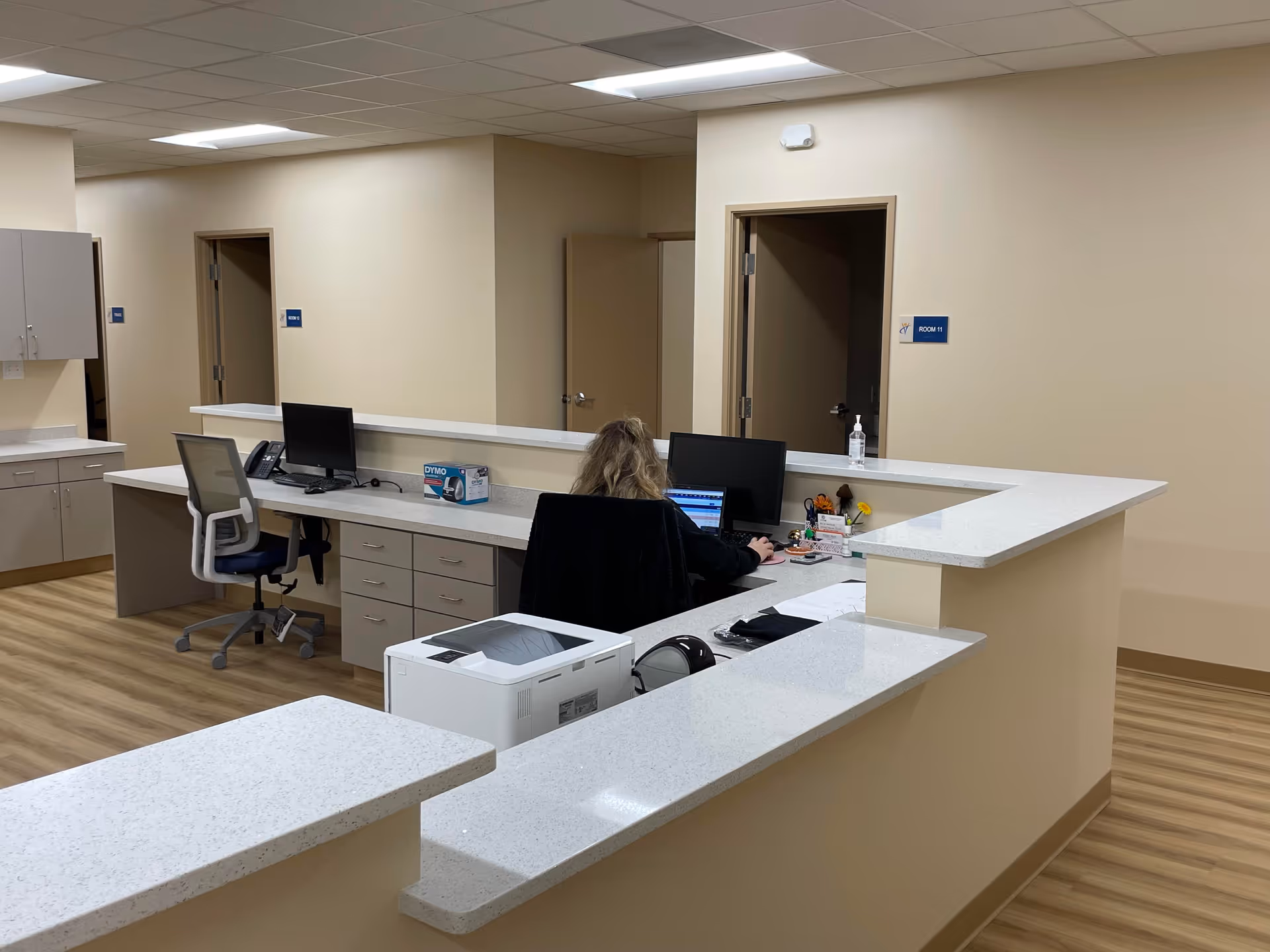 Reception desk with computers and a staff member in a medical office lobby.