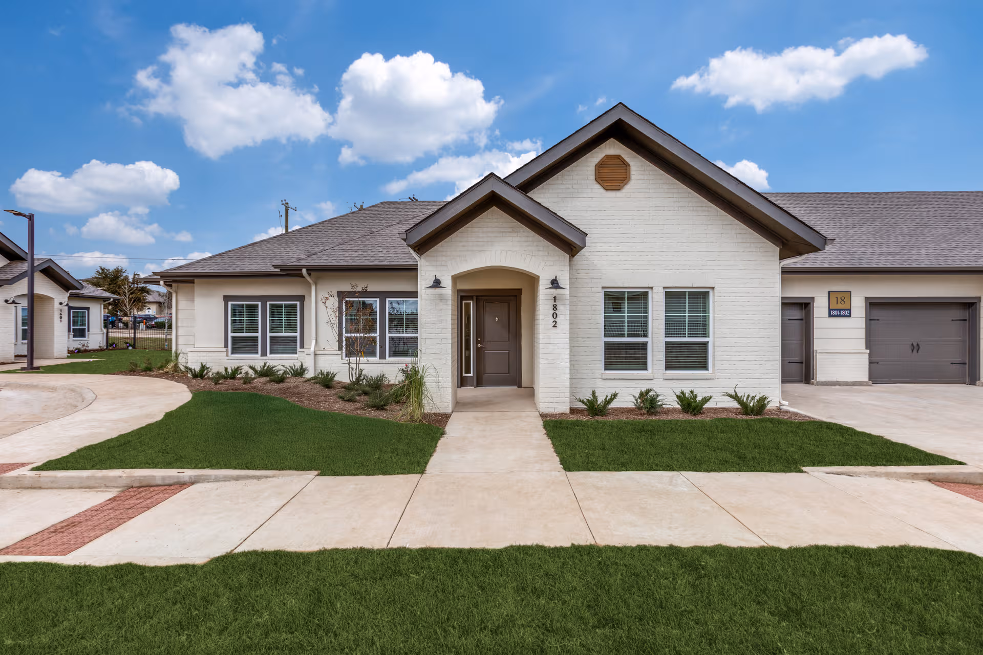 White, single-story senior living facility with a centered entry and manicured lawn.
