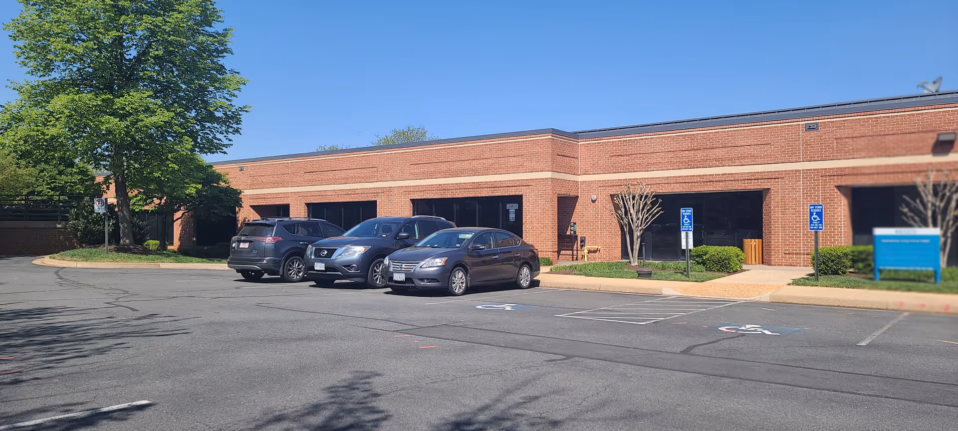 Exterior view of Aspirational Living LLC facility with brick facade and parked cars.