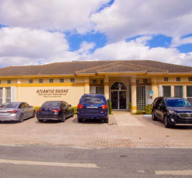 Front view of Atlantic Shore Retirement Residence with parked cars and a clear entrance.