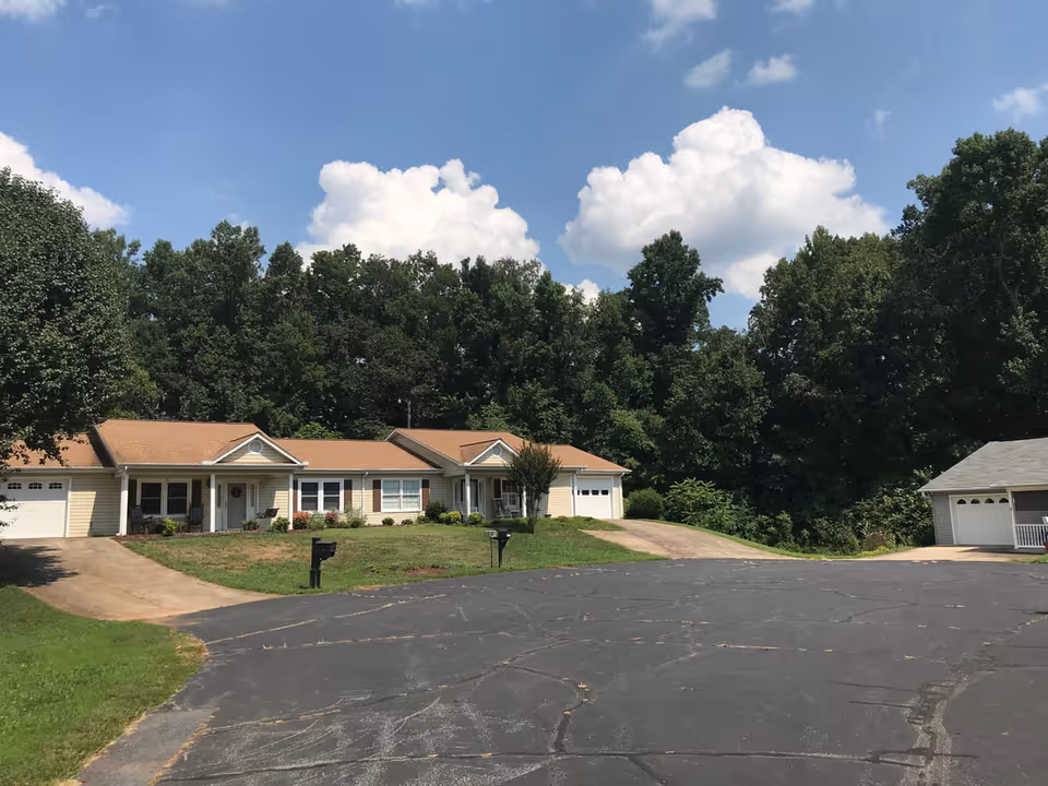 Front view of a single-story senior living facility with garages and trees.