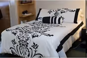 A neatly made bedroom featuring a bed with black-and-white floral bedding.