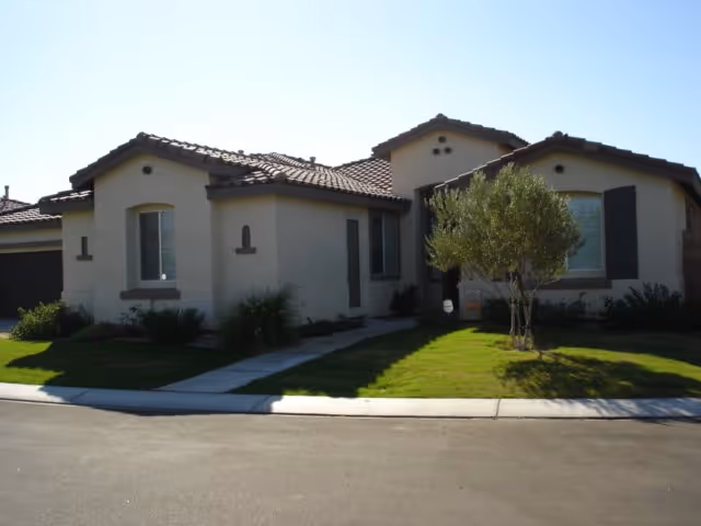 Front exterior of a single-story beige building with a tiled roof and lawn.