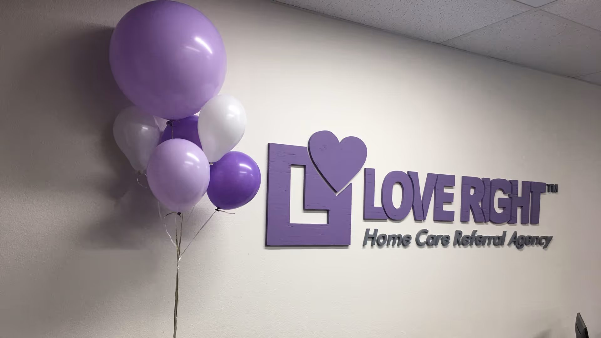 Interior wall with purple Love Right sign and balloons in care agency