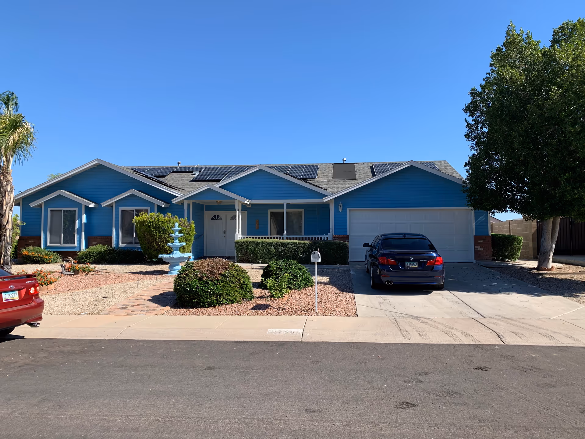 Blue single-story building with a front yard, fountain, and a parked car.