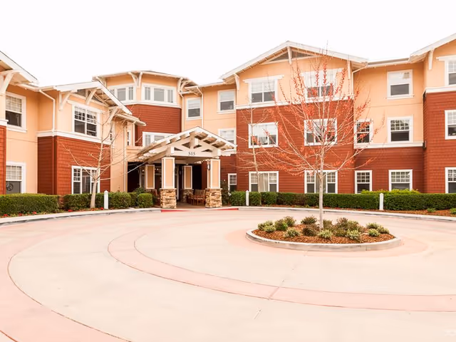 Exterior view of Elder Care Alliance facility with circular driveway and entrance canopy.