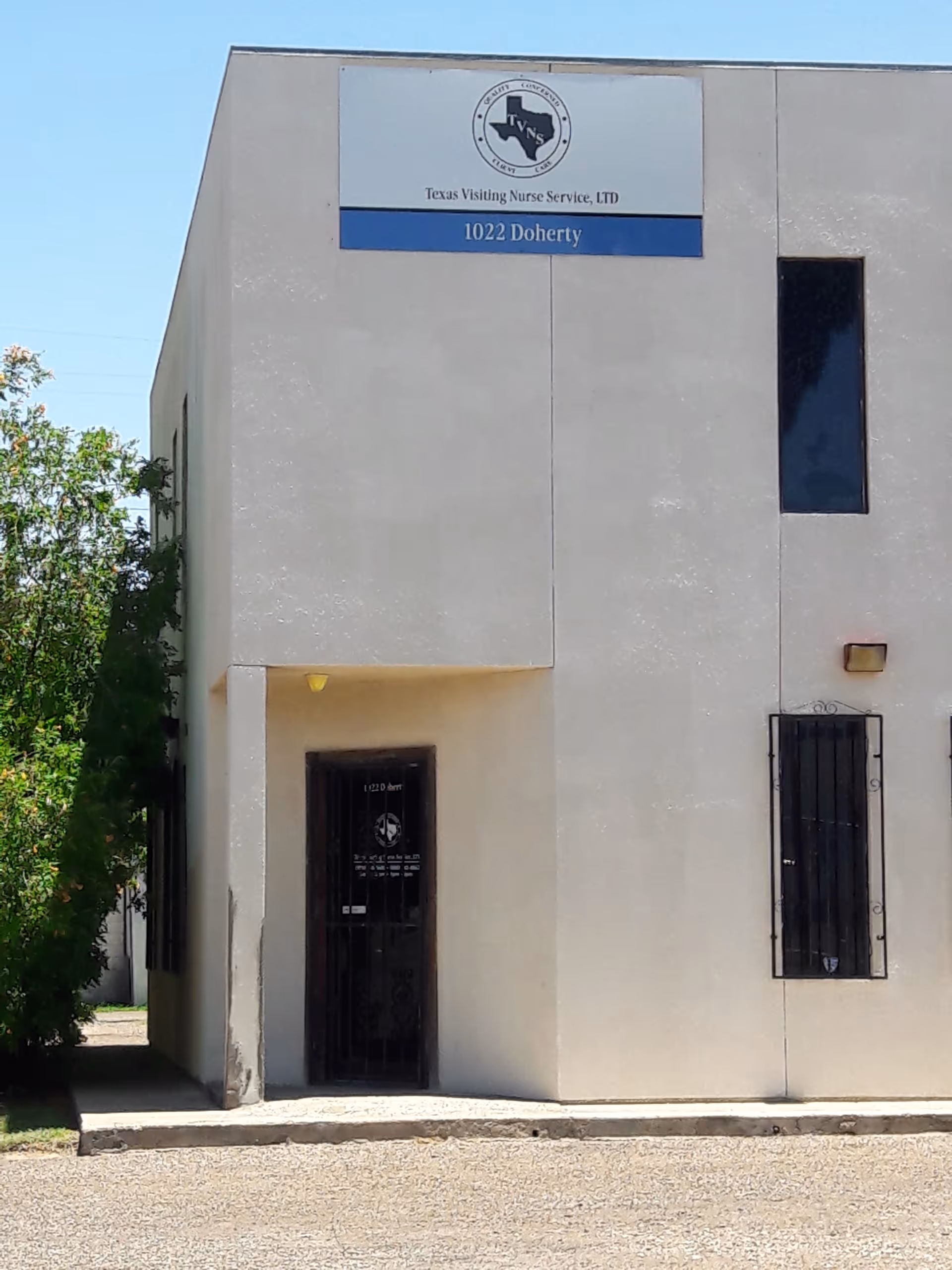 Front view of TVNS Mission building with sign, entrance, and barred windows.