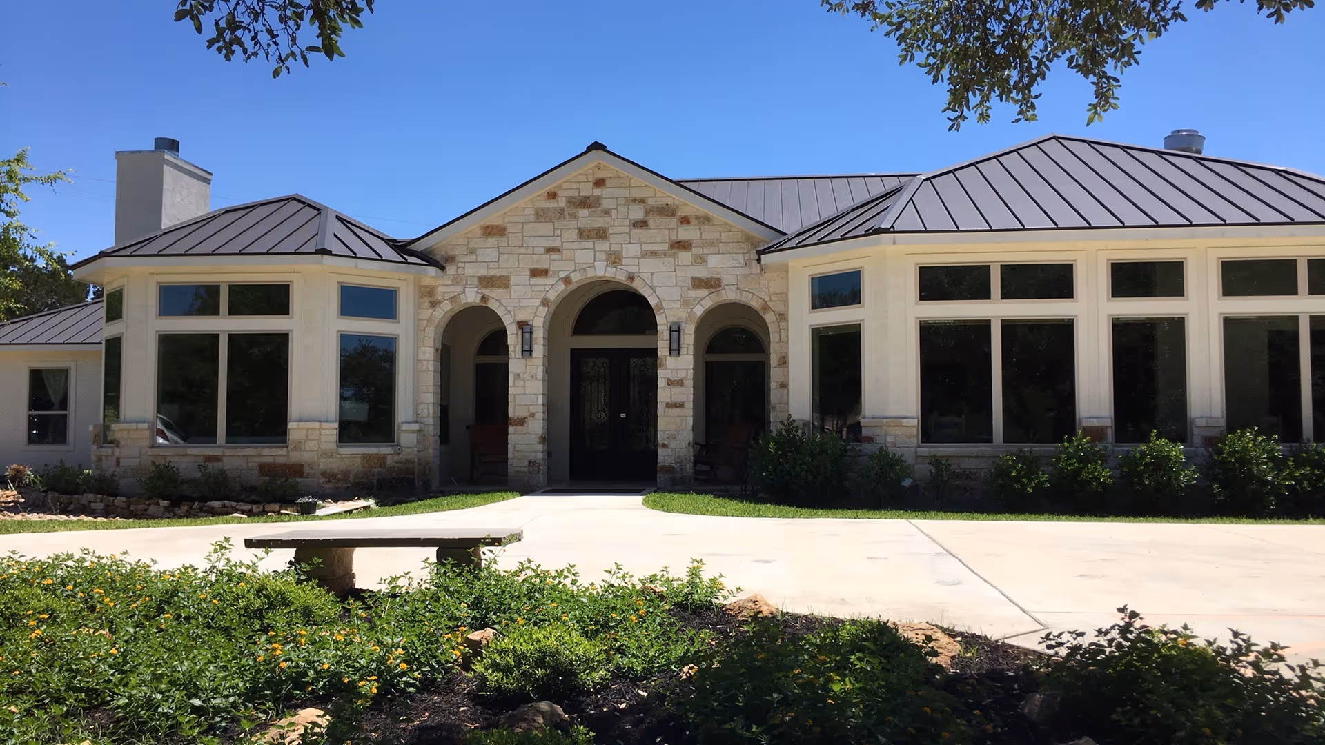 Stone-clad senior living facility exterior with arched entrance and large windows.