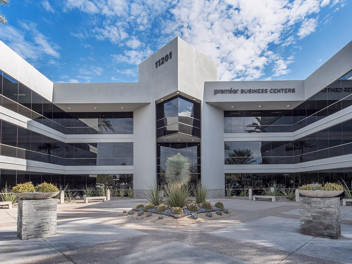 Modern glass-front building with central entrance and desert landscaping.