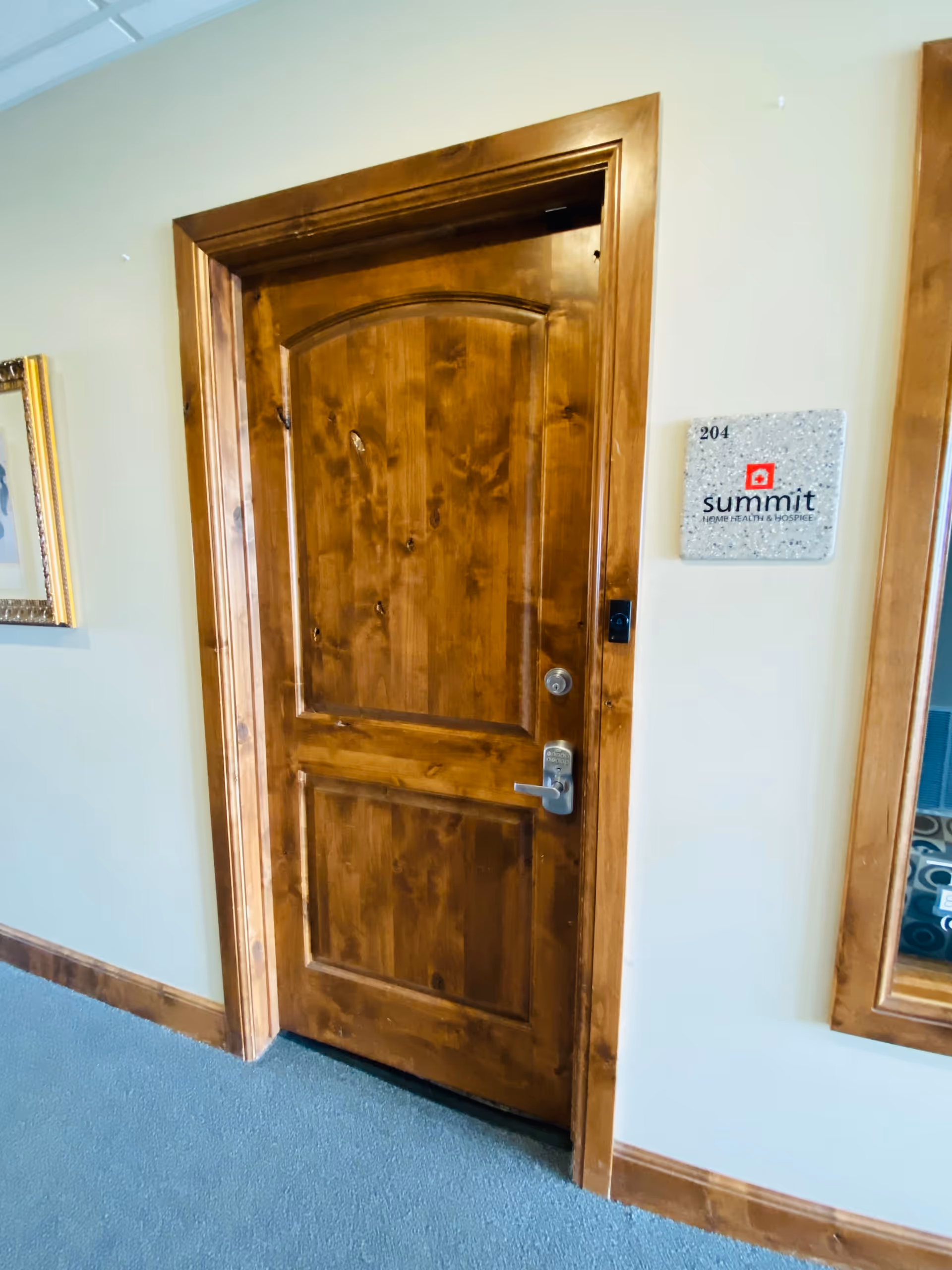 Wooden interior door in a hallway with a room plaque labeled 204 Summit