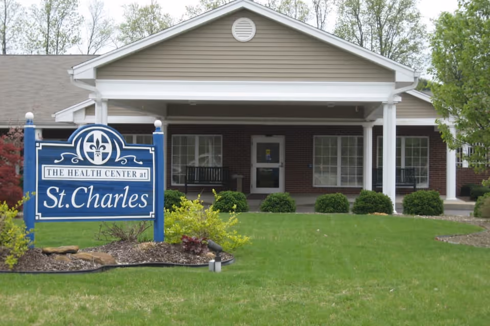 Front entrance of The Health Center at St. Charles with a blue sign on the lawn and a covered portico.