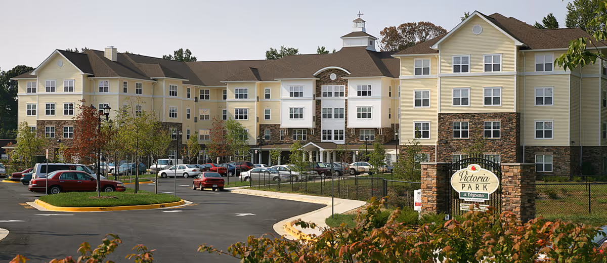Exterior view of Victoria Park at Edgewater showing a multi-story building, parking lot, and entrance sign.