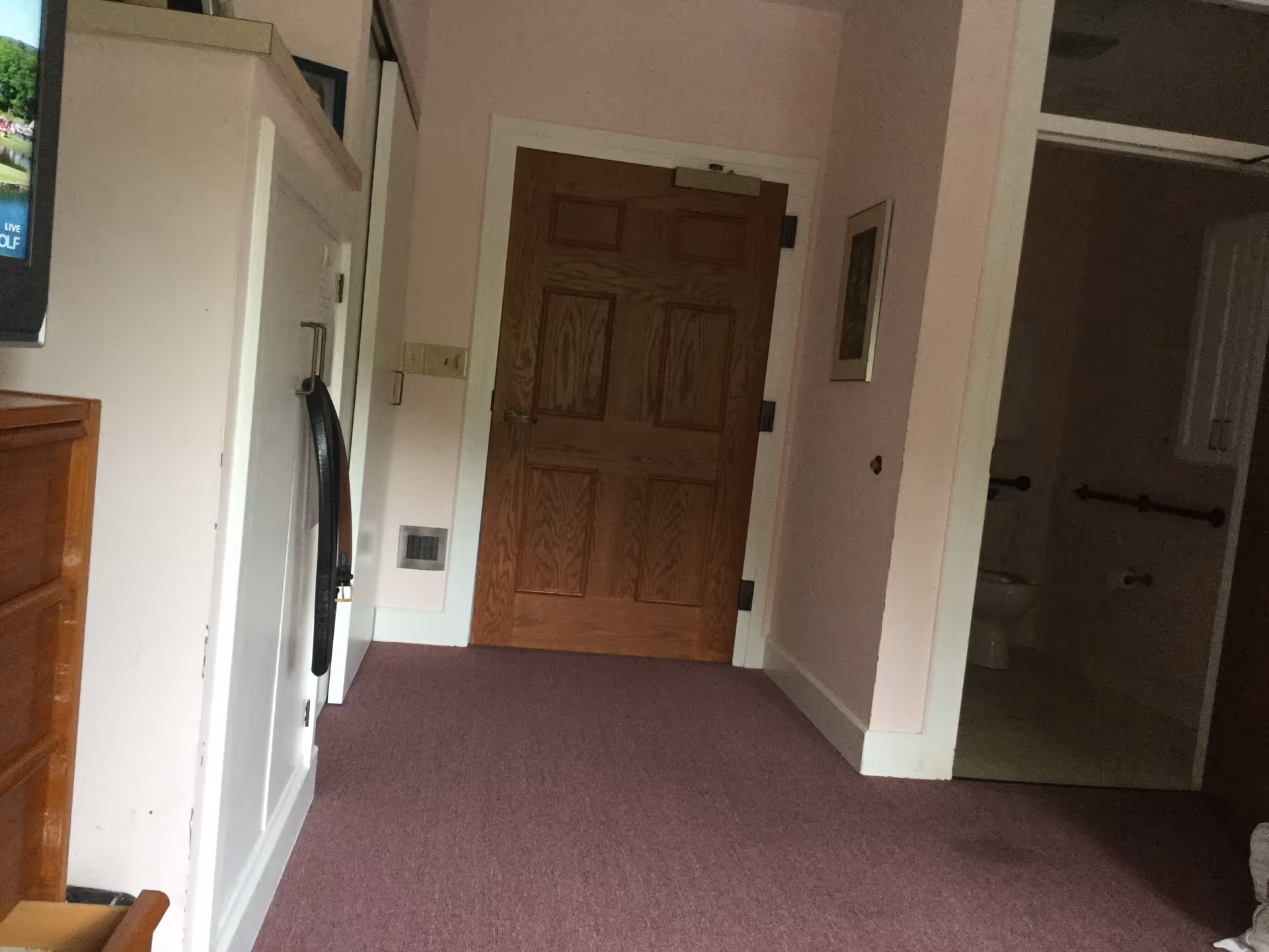 Hallway inside Mayflower Care Center with wooden door and visible bathroom.