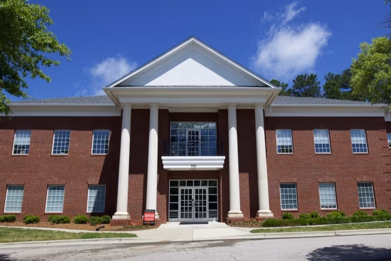 Brick building with tall white columns and a glass front entrance.