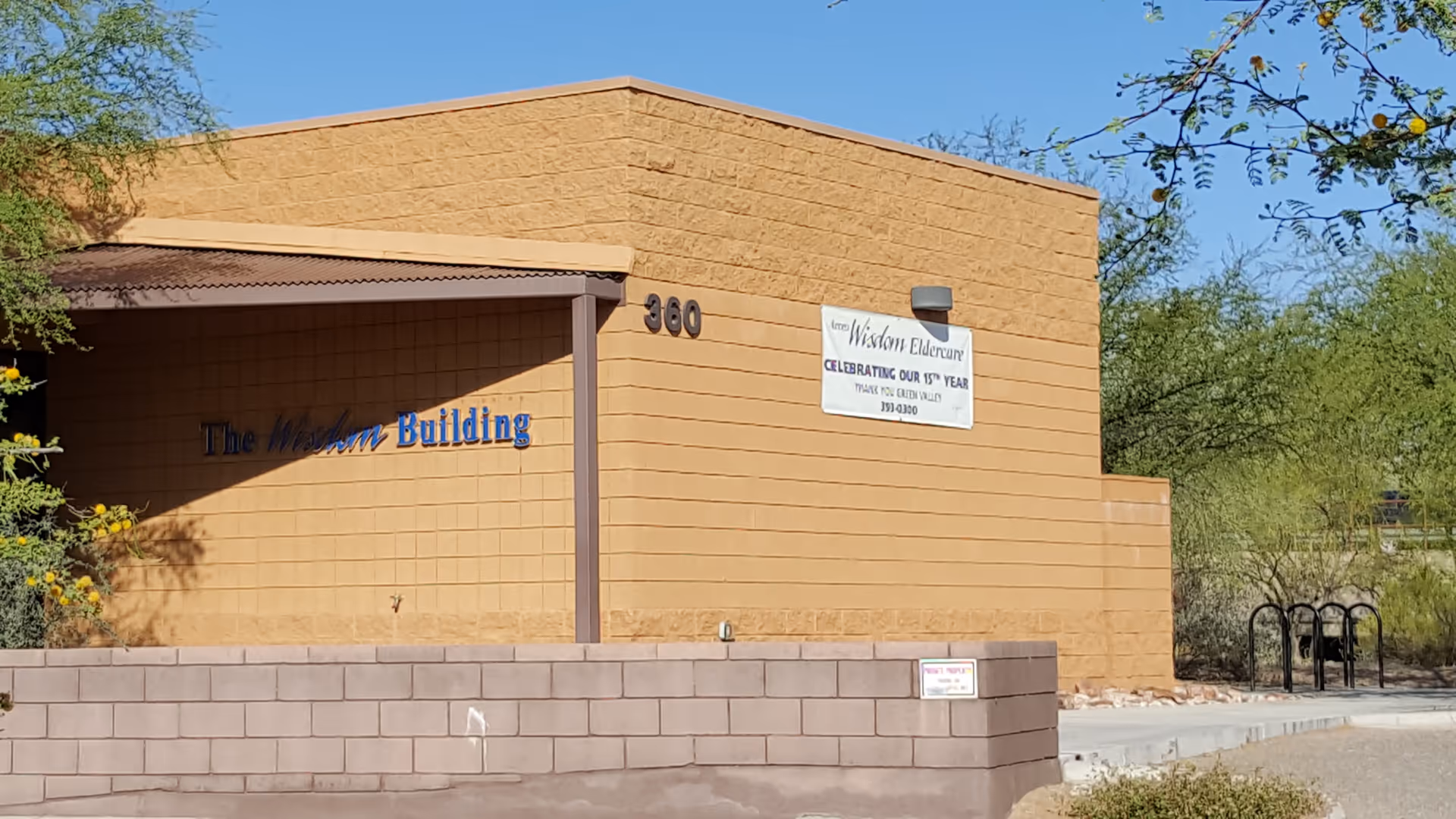 Exterior view of The Wisdom Building with a banner on the tan brick wall.
