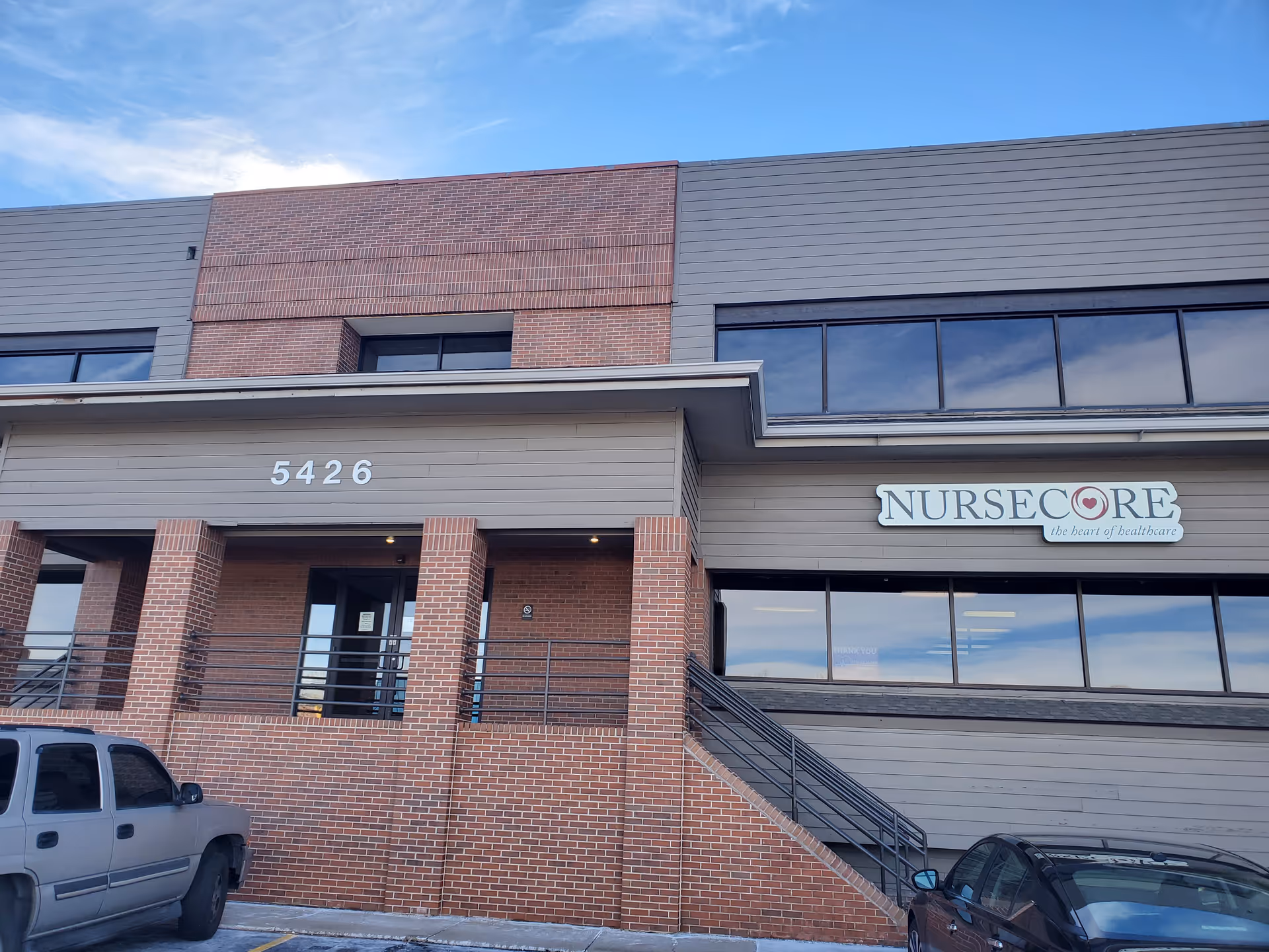 Exterior view of a NurseCore building with brick facade, entrance stairs, and parking.