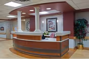 Reception desk with burgundy accents sits in a medical facility lobby.