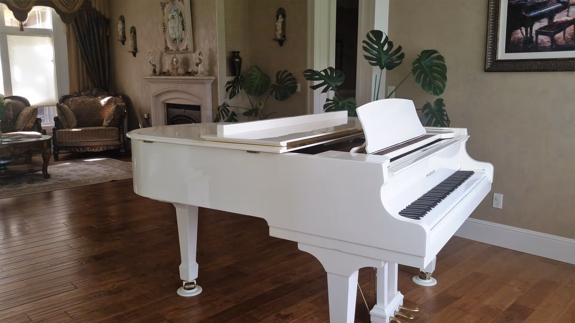 White grand piano in a warmly furnished living room with plants and seating.