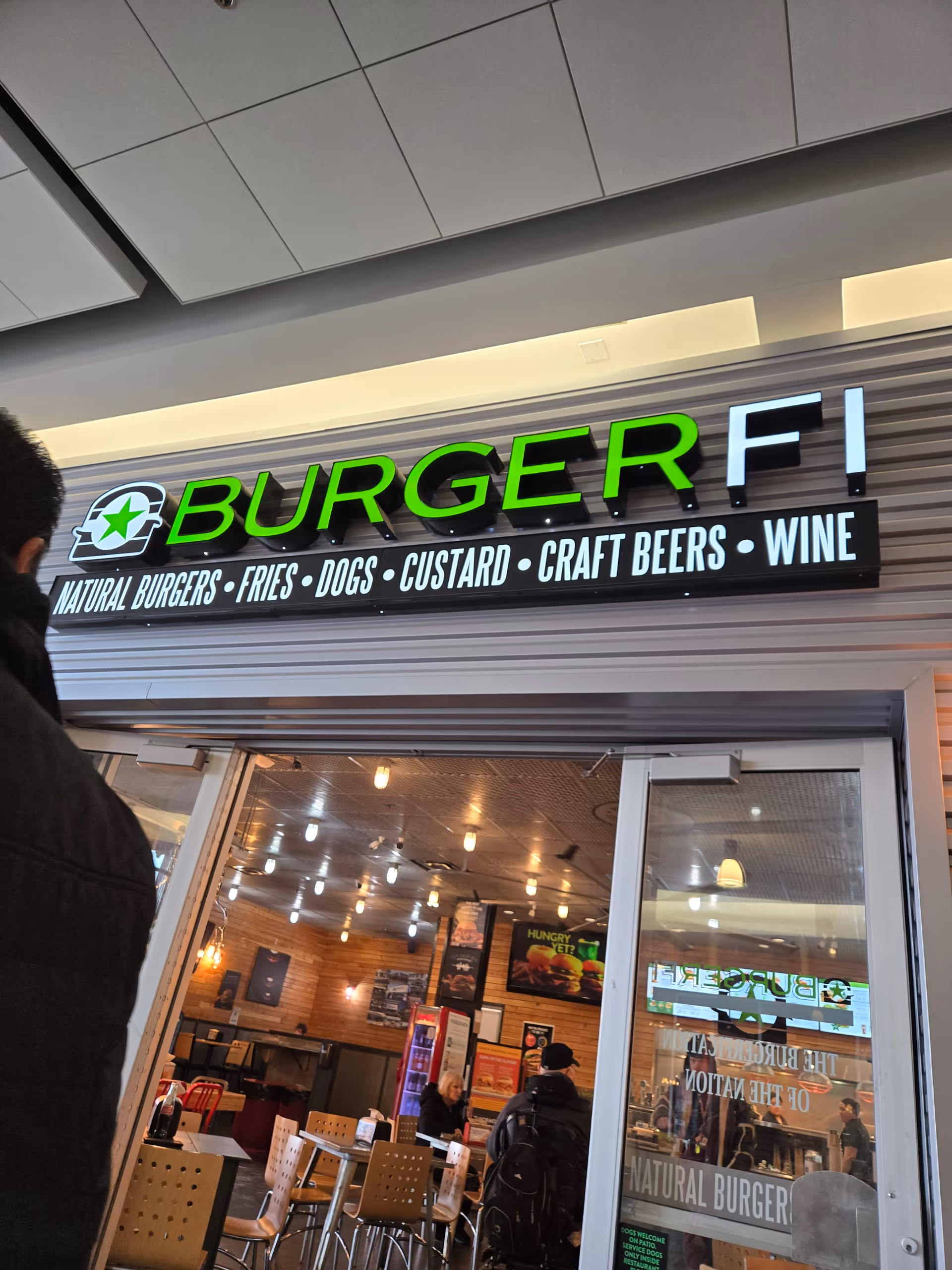 Interior of a BurgerFi restaurant with diners and seating.