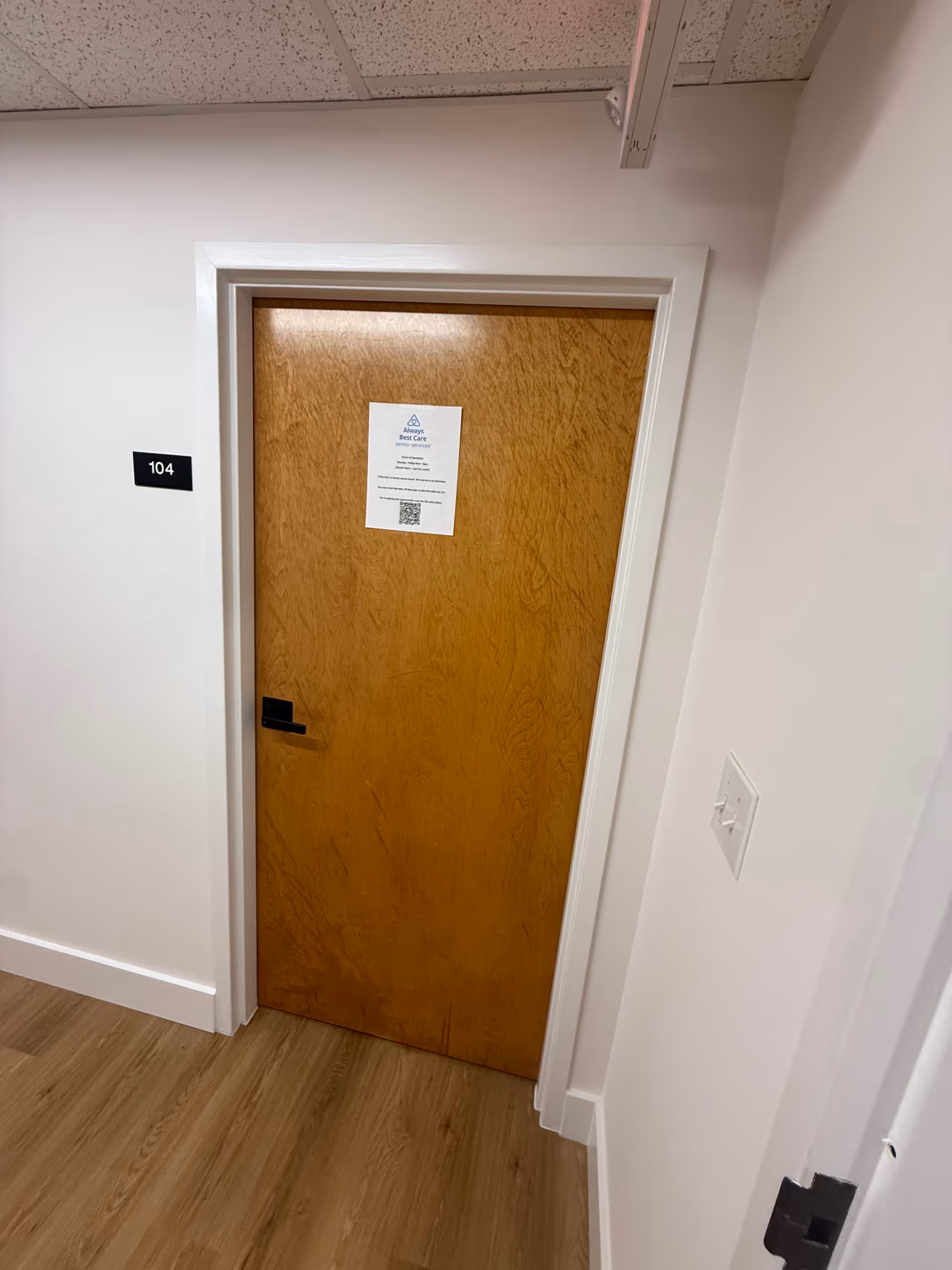 Wooden door labeled 104 in a clean hallway of a senior facility.