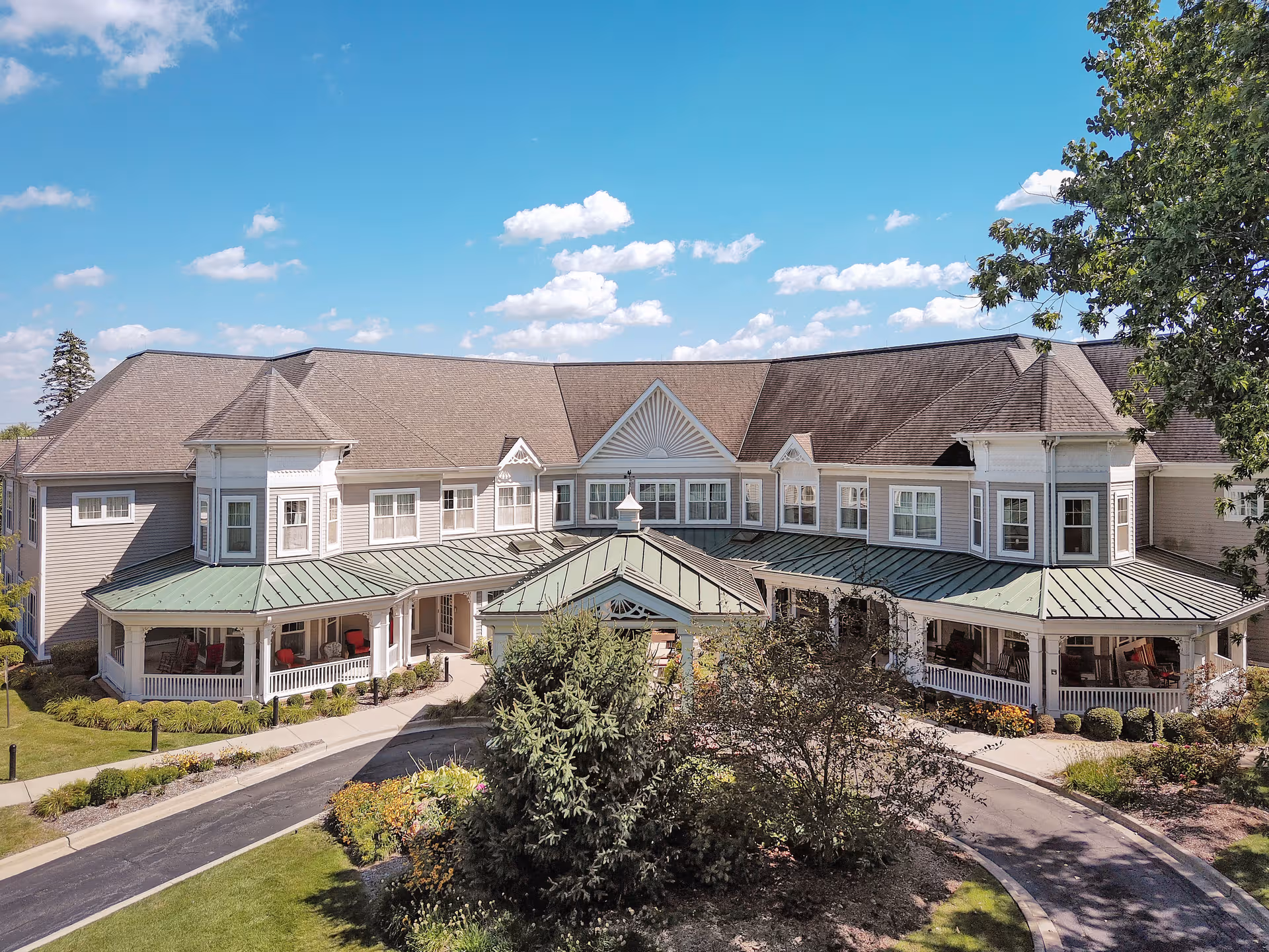 A large, multi-wing senior living facility with wraparound porches and landscaped grounds.